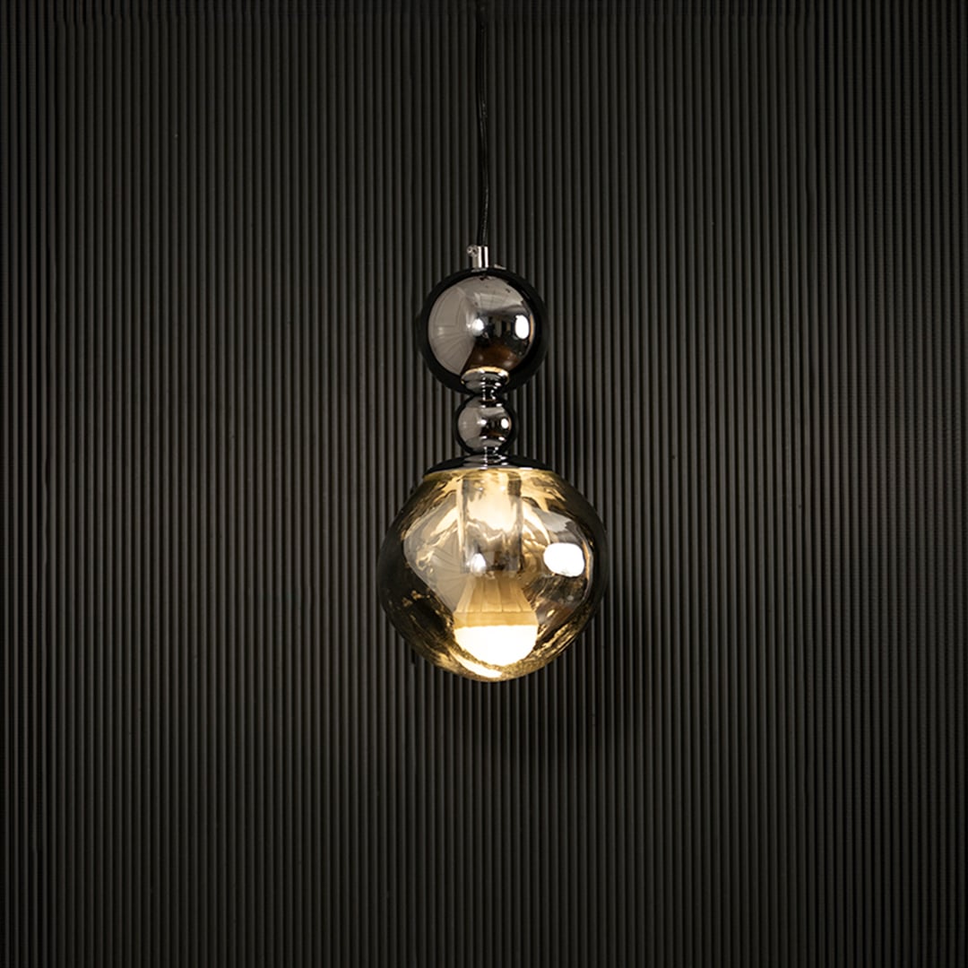 Elegant silver chrome pendant light illuminated on dark background highlighting luxurious reflective metallic finish.
