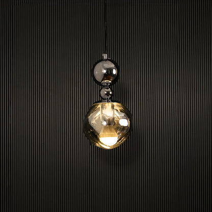 Elegant silver chrome pendant light illuminated on dark background highlighting luxurious reflective metallic finish.