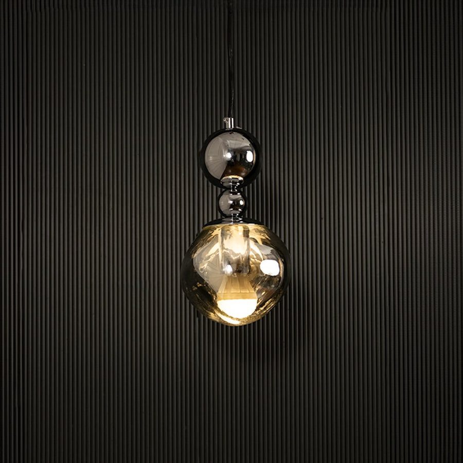 Elegant silver chrome pendant light illuminated on dark background highlighting luxurious reflective metallic finish.