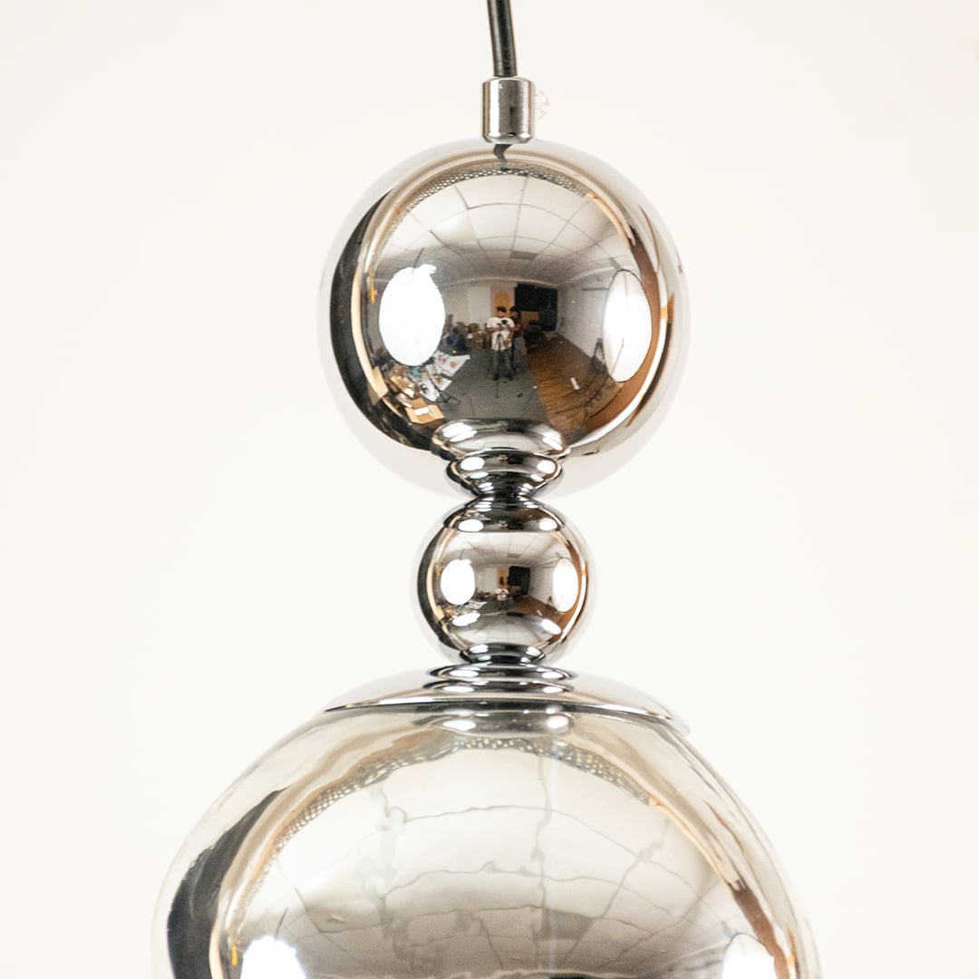 Close view of glass pendant light with chrome metal detailing highlighting premium finish and modern ceiling lighting decor style.