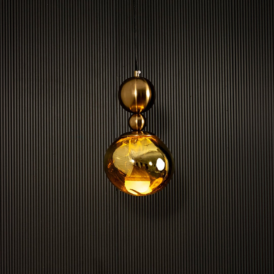 Elegant gold pendant light illuminated beautifully on dark background highlighting rich metallic golden sheen.