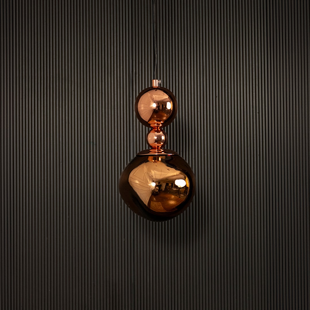 Polished copper pendant light displayed on dark background with lights off highlighting its luxurious finish.