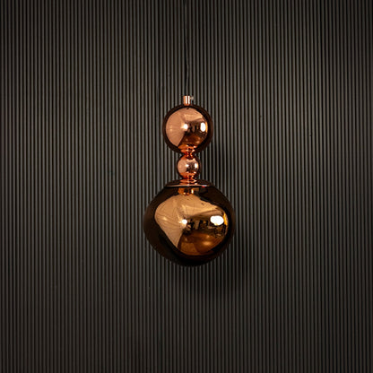 Polished copper pendant light displayed on dark background with lights off highlighting its luxurious finish.