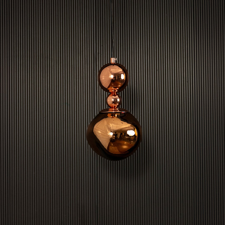 Polished copper pendant light displayed on dark background with lights off highlighting its luxurious finish.