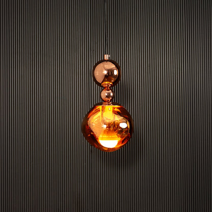 Elegant copper pendant light illuminated on dark background highlighting rich metallic sheen and artistic design.