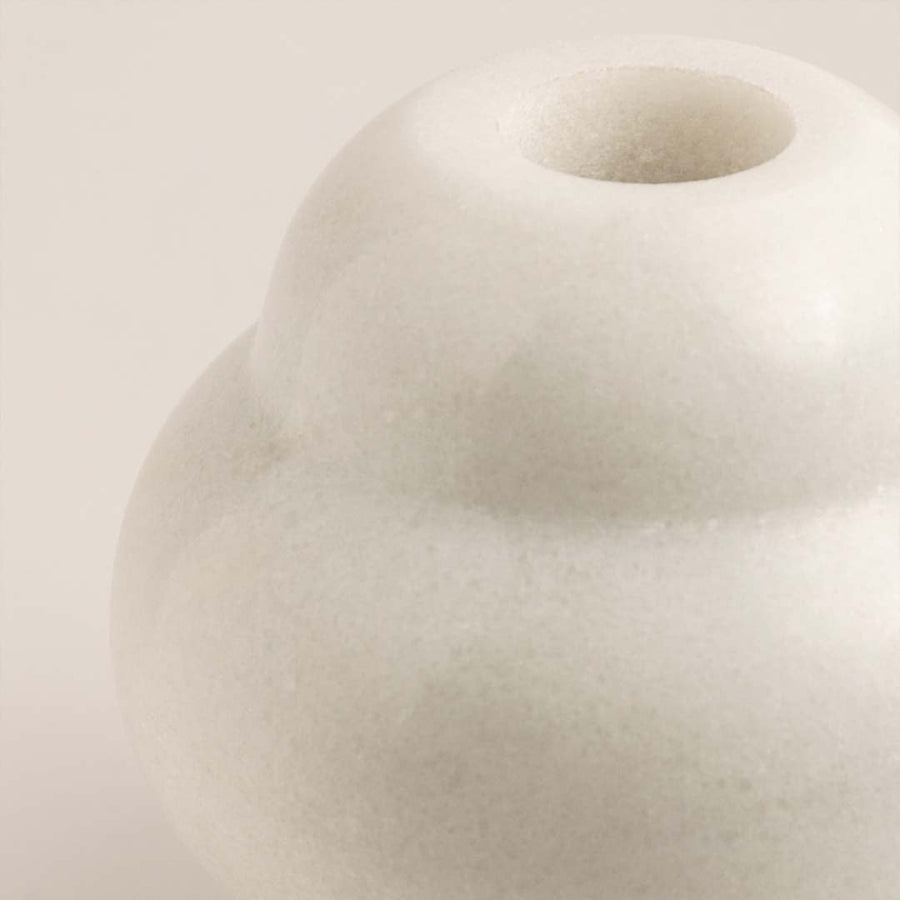 Detailed closeup of the smooth surface and curved form of the white ceramic vase.