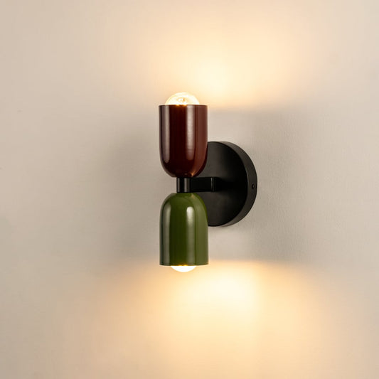 Modern dual tone wall light in red and green with black base glowing on white background perfect for home interiors.