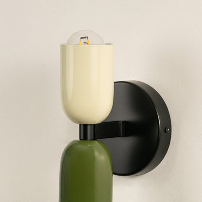 Closeup of contemporary green and cream wall light showing sleek matte finish and elegant curved shades.