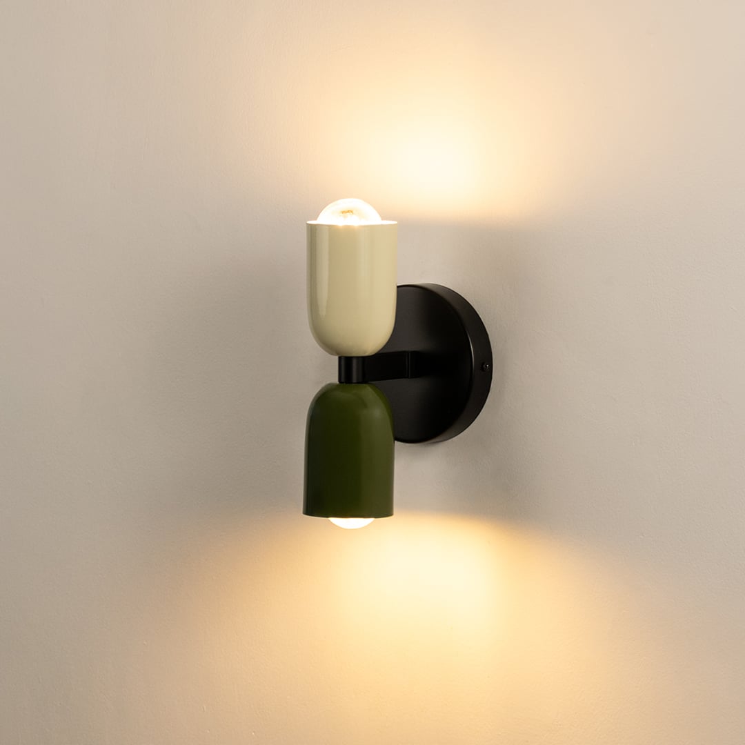 Modern two-tone wall light with cream and green shades glowing softly on white wall perfect for stylish interiors.