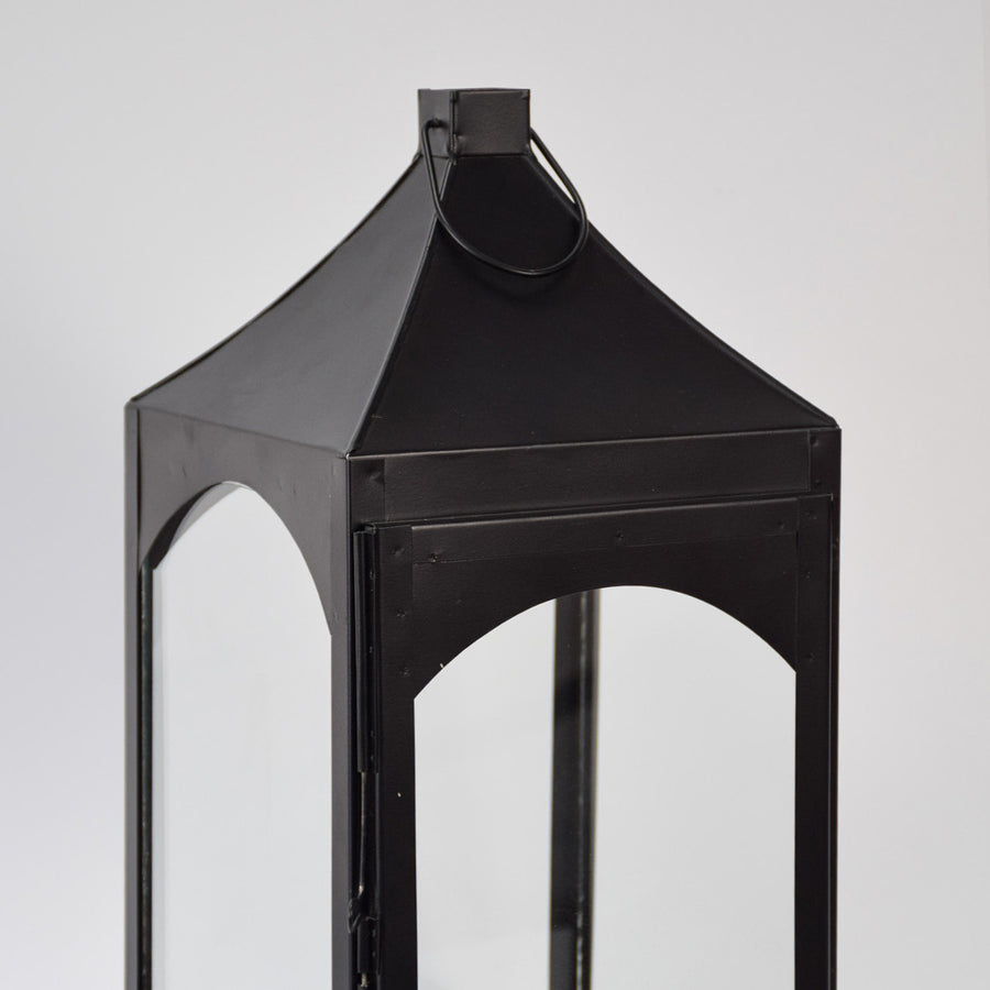 Closeup of black metal lantern with angular top and glass panels for luxury decor styling use.