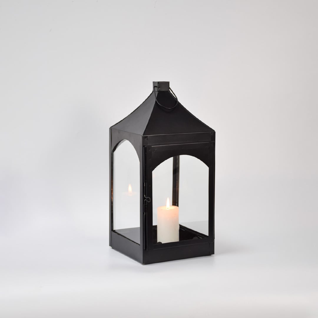 Black metal and glass lantern with candle unlit on white background highlighting solid frame clean edges and modern lantern design.