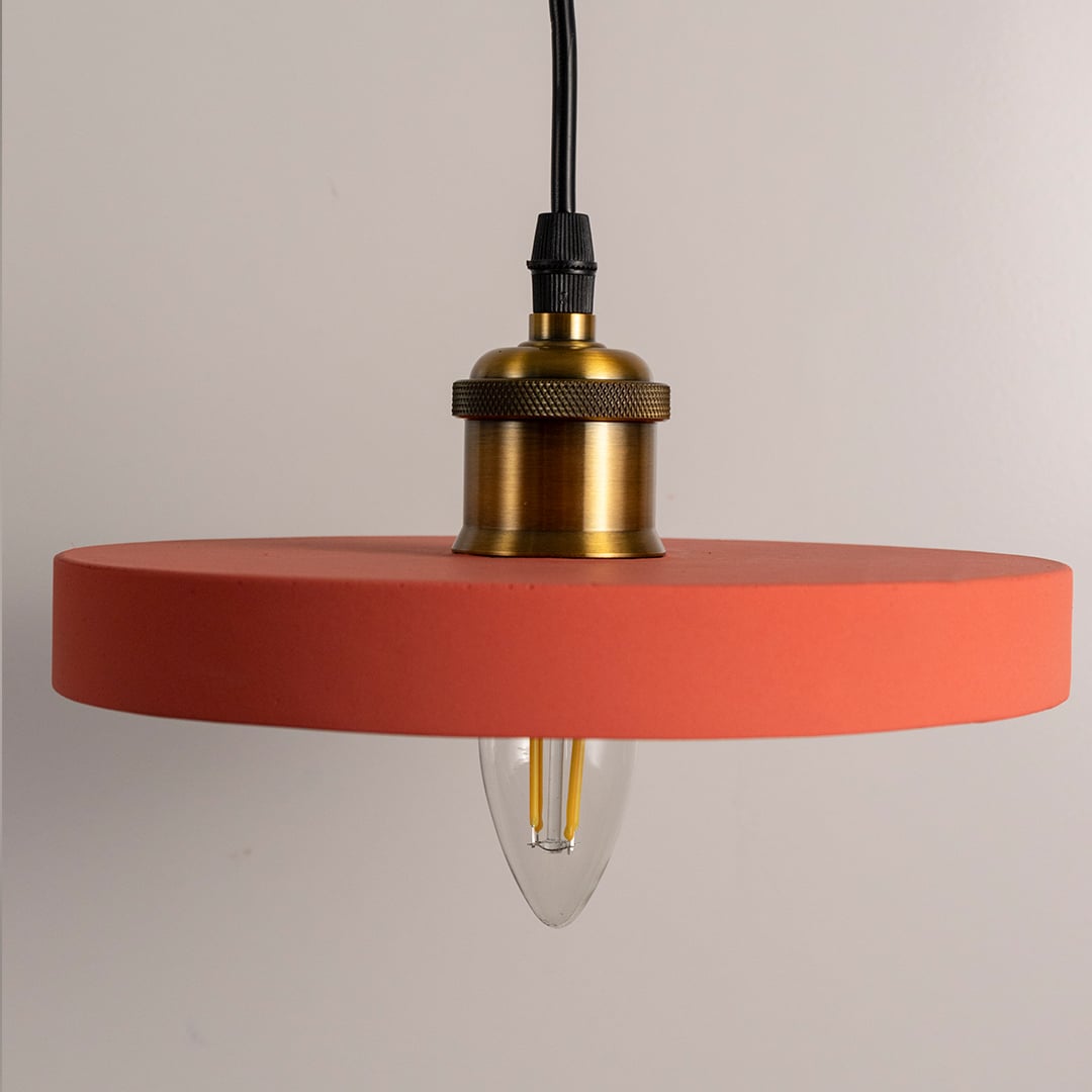 Terracotta pendant light with smooth matte finish and golden brass socket displayed with the bulb turned off.