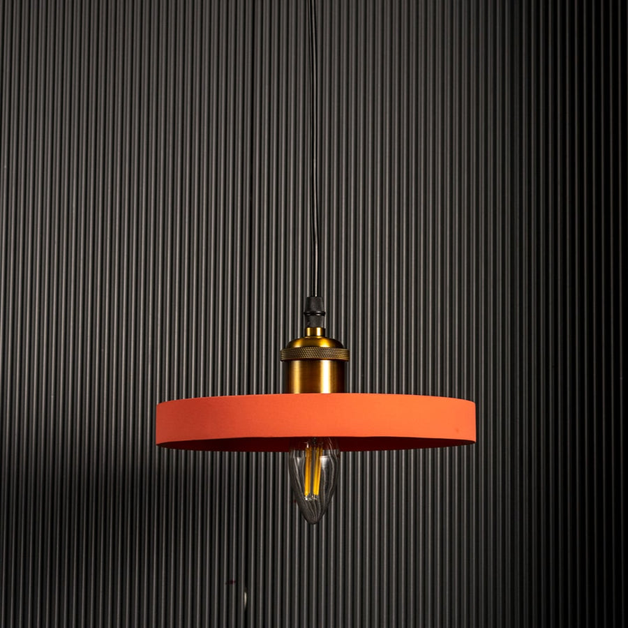 Designer pendant light with wide orange metal shade and gold detailing glowing against black backdrop for bold modern interiors.