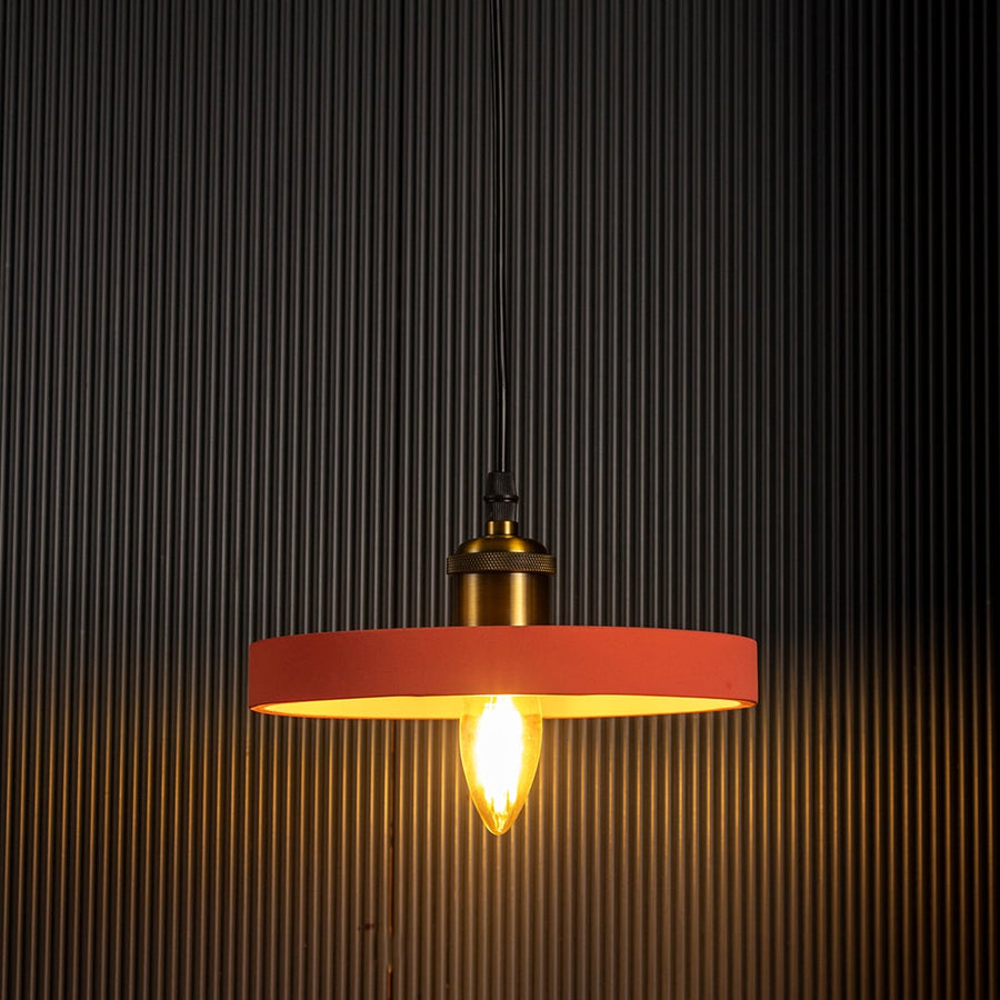 Terracotta pendant light glowing brightly with warm illumination highlighting its modern design against a dark backdrop.