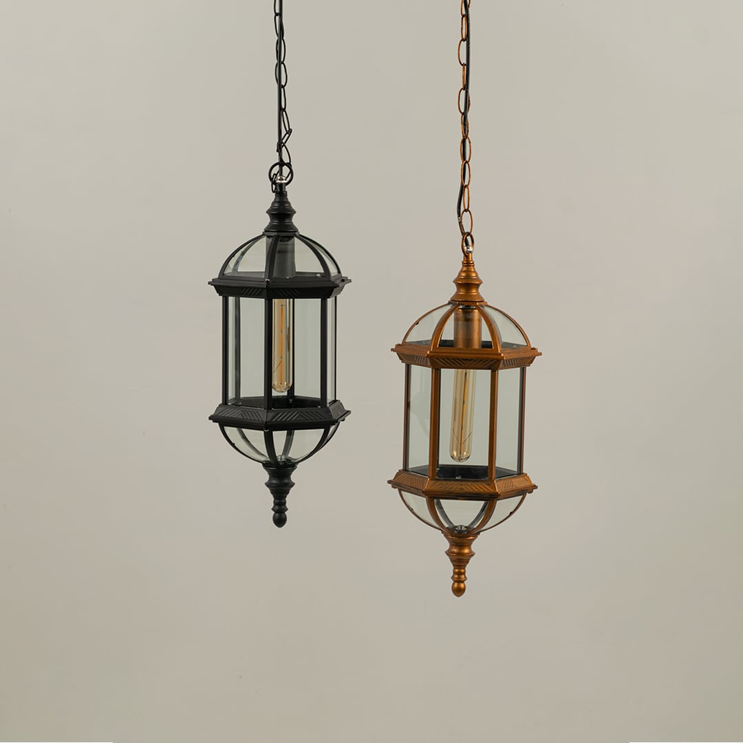 Two unlit classic garden hanging lamps in black and gold metal finishes suspended side by side against a plain white studio backdrop.