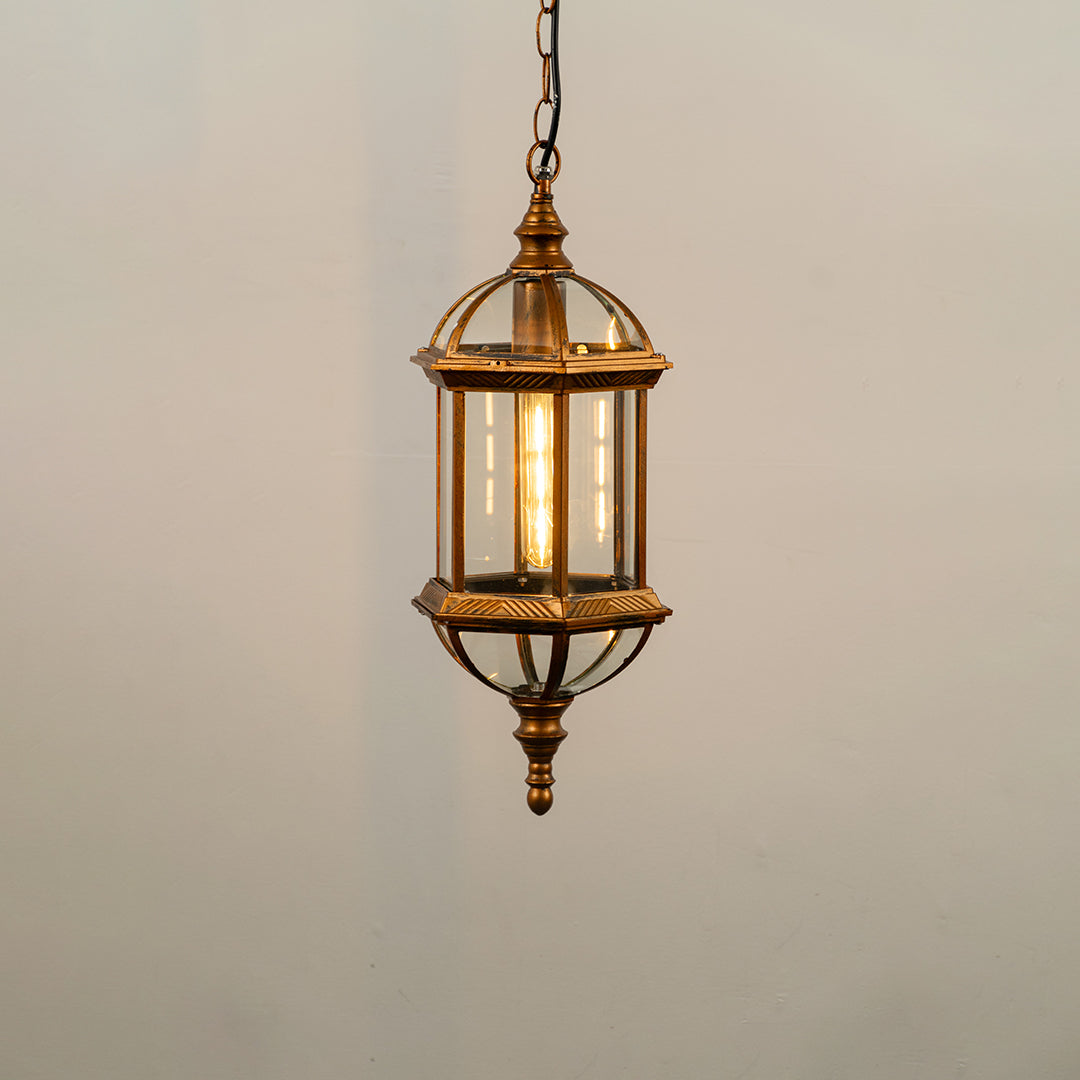 Gold metal hanging outdoor lantern with glass enclosure glowing on white background ideal for porch entrance and exterior decor lighting.