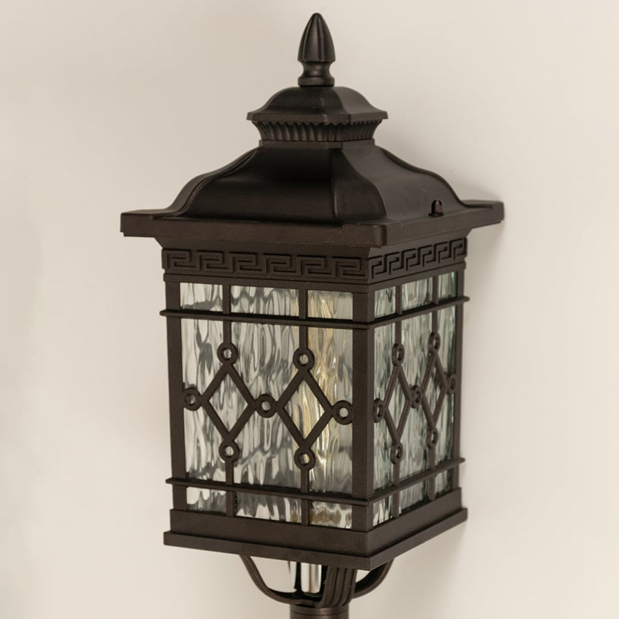 Closeup of black metal spike lantern showing patterned glass and decorative top finial suitable for elegant garden and pathway lighting.
