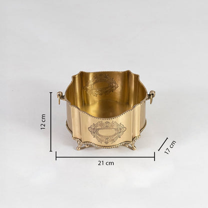 Top view of round floral etched brass planter with detailed borders and decorative handles on plain backdrop.