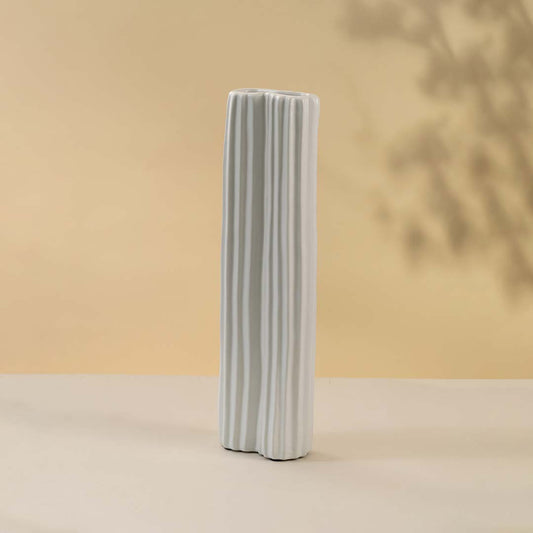 White ceramic decorative vase with vertical ribbed texture for minimalist shelf styling and modern home decor.