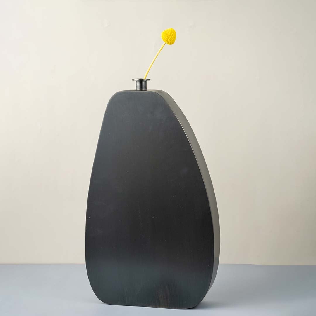 Tall black wooden vase with smooth matte finish styled with yellow flower for modern home and office decor.