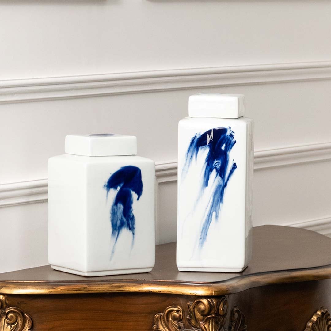 White ceramic jars with blue brushstroke artwork placed on a console for artistic modern décor styling.