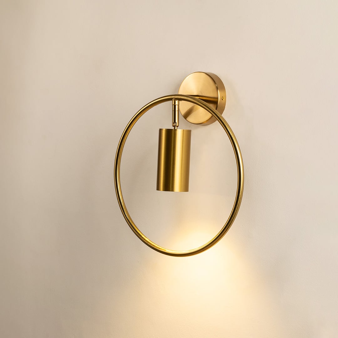 Gold ring wall sconce glowing softly against a clean white background showcasing minimalist modern lighting design perfect for refined interior home decor.