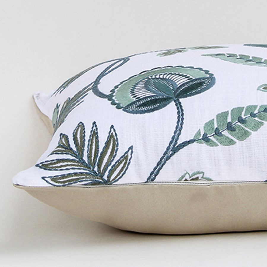 Closeup of the cushion highlighting the detailed green floral embroidery and textured fabric surface.