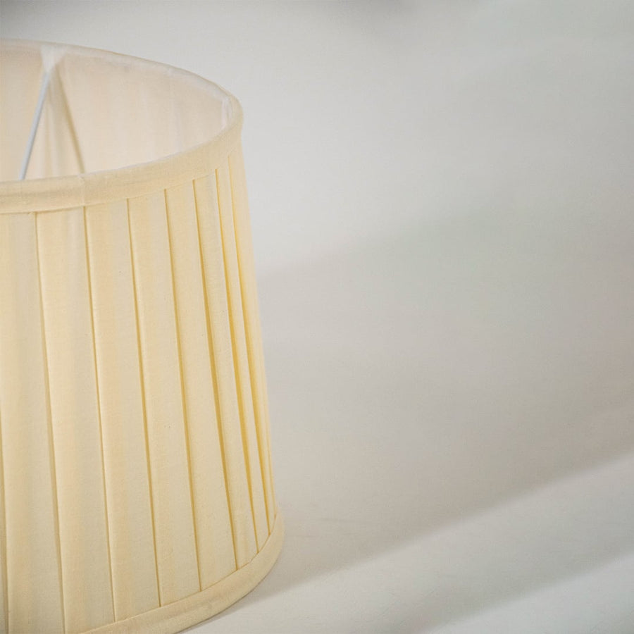 Closeup view of the cream pleated lampshade showing fine fabric folds and smooth detailing for a clear and graceful product presentation.