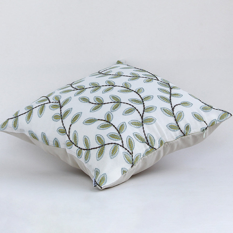 Soft cotton cushion cover with green leaf embroidery shown at an angle offering a fresh nature inspired décor accent with a breathable gentle and skin friendly fabric finish ideal for modern interiors.