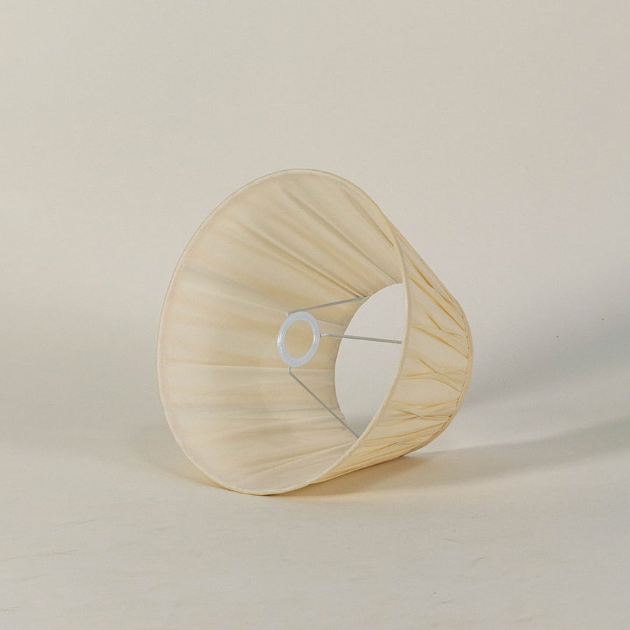 Cream pleated lampshade displayed on a clean white background highlighting its soft folds and classic tapered shape with smooth detailing.