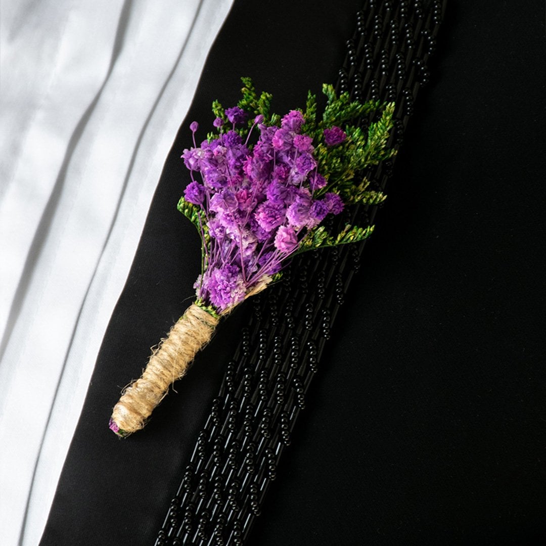 Closeup of preserved purple flower bouquet with green leaves wrapped in natural jute – artificial decorative flower.