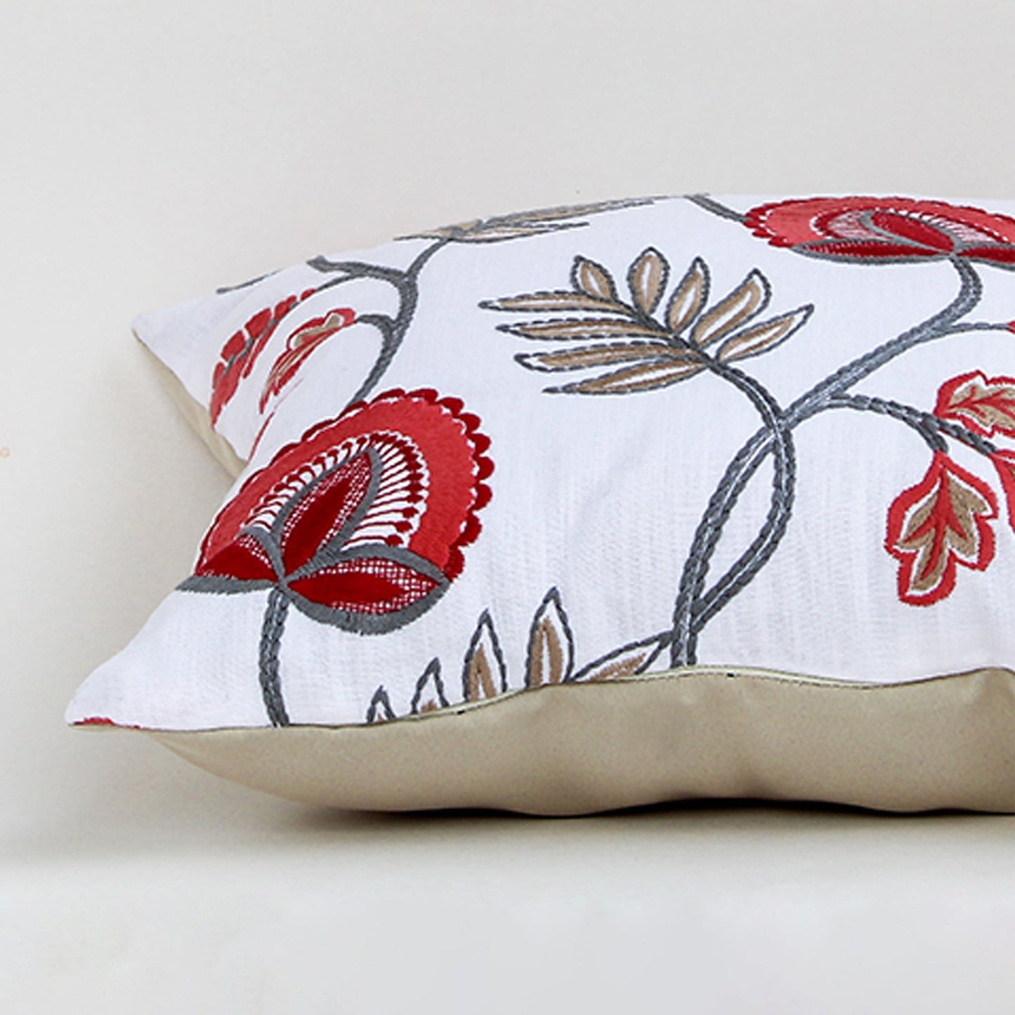Soft cotton cushion cover with red and blue embroidered floral design shown at an angle offering a striking nature inspired décor style with a breathable smooth and skin friendly fabric feel.