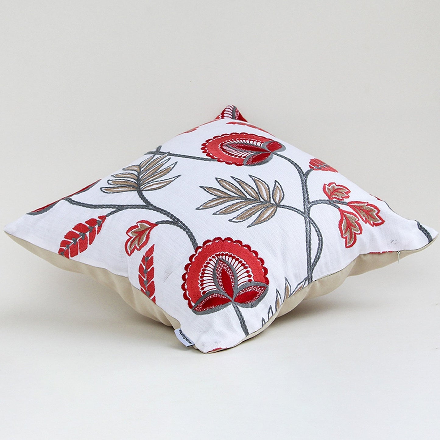 Soft cotton cushion cover with red floral embroidery displayed at an angle offering a lively nature inspired décor style with a breathable smooth and skin friendly material finish.