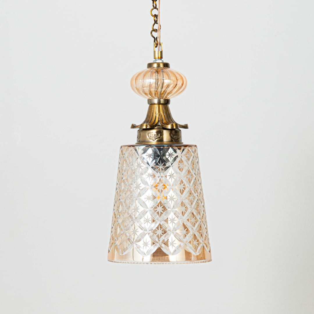 Patterned glass and gold metal pendant light with warm glow for elegant home decor interiors.
