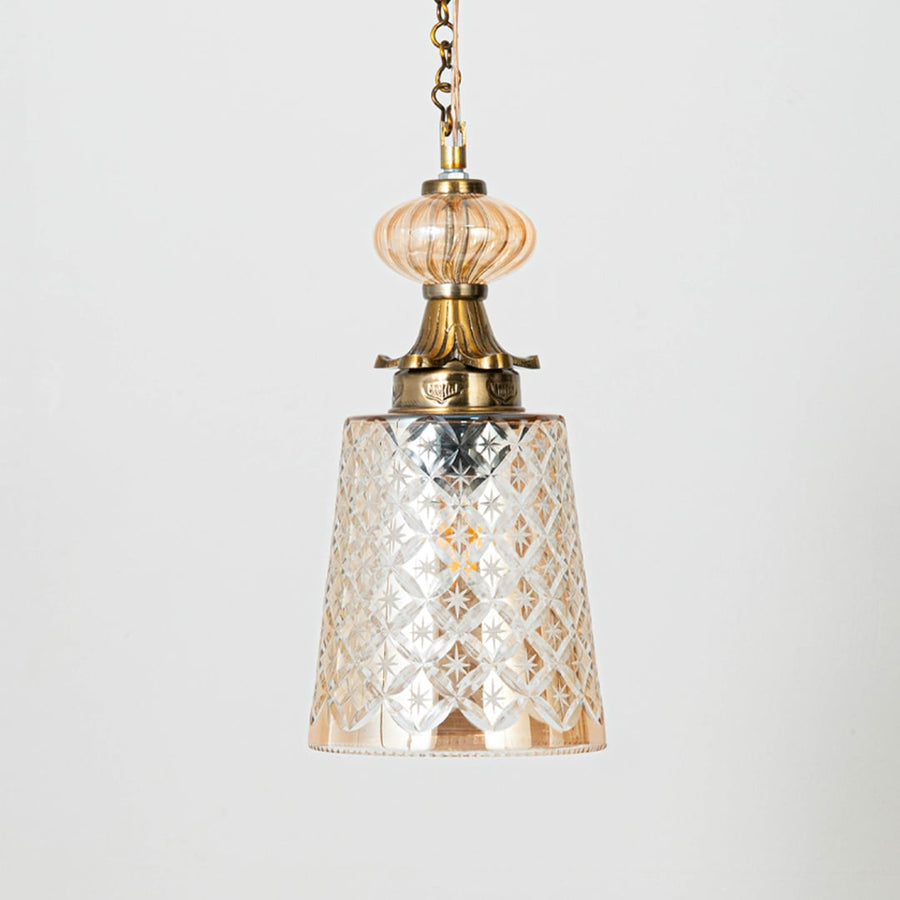 Patterned glass and gold metal pendant light with warm glow for elegant home decor interiors.