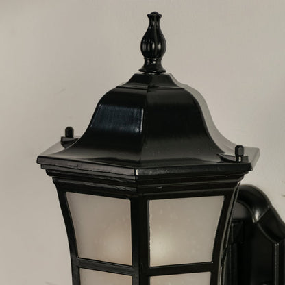 Closeup of black metal outdoor lantern showing frosted glass and elegant curved arm detail perfect for enhancing home entrance porch and patio Decor.