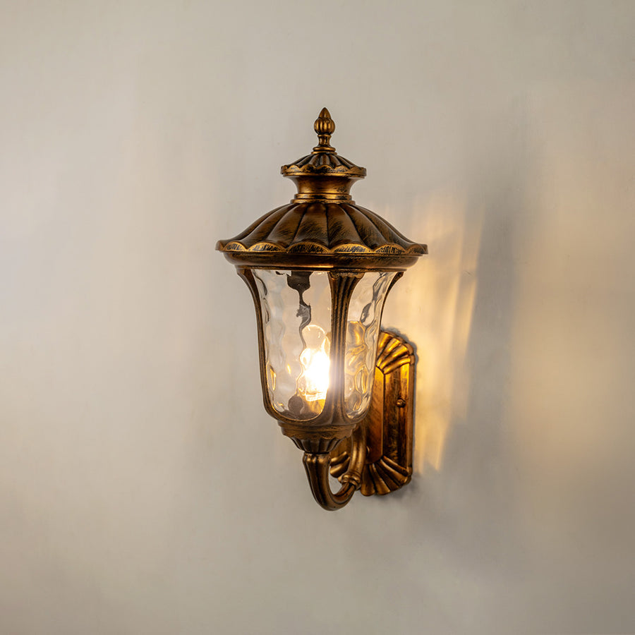 Vintage bronze outdoor wall light glowing on white wall for classic exterior entryway lighting decor.