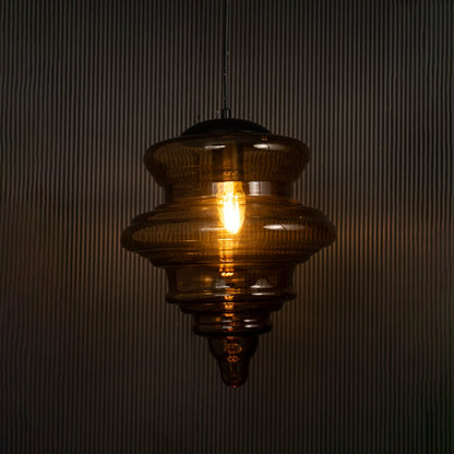Elegant amber glass pendant hanging light illuminated on dark background highlighting its artistic craftsmanship and warm ambient glow.