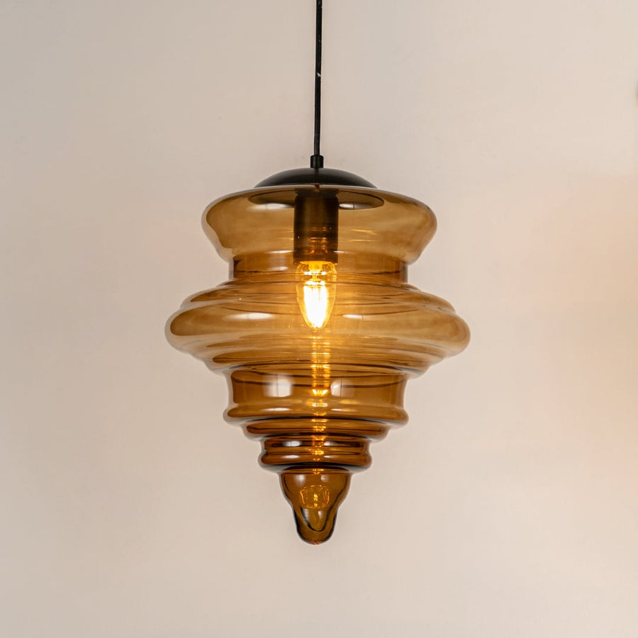 Amber ribbed glass pendant light with layered glass design and exposed bulb for warm modern ceiling lighting.