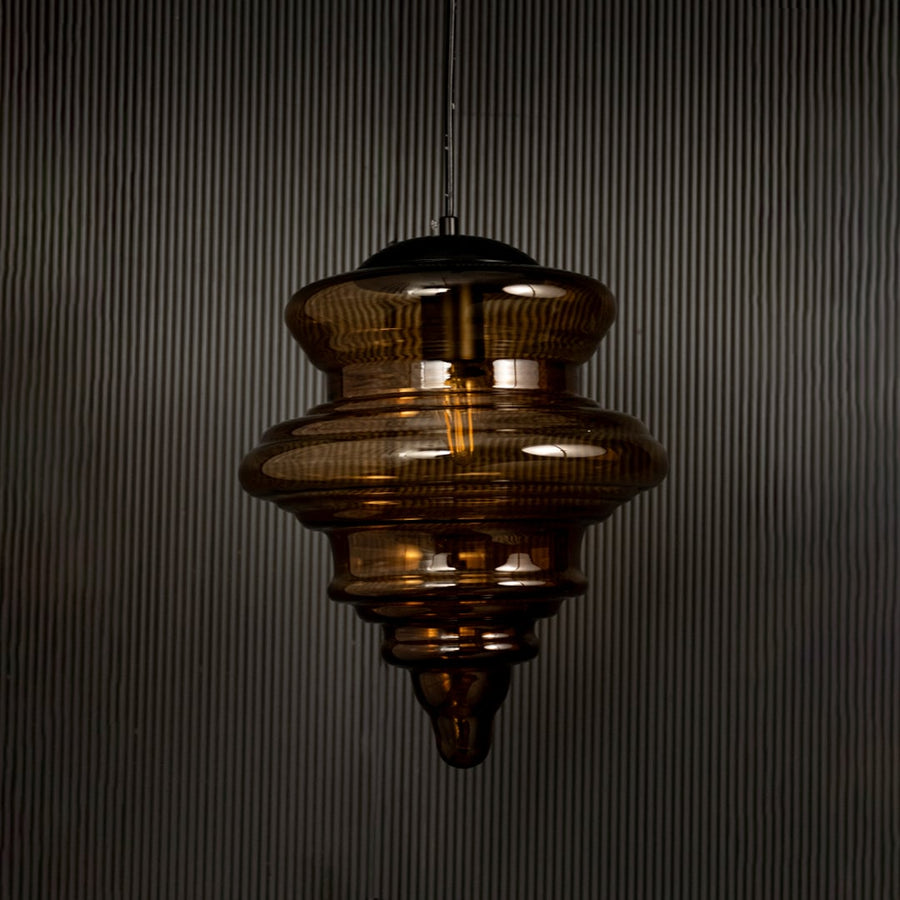 Amber glass pendant light displayed on dark background with lights off highlighting its glossy texture and sculptural design.