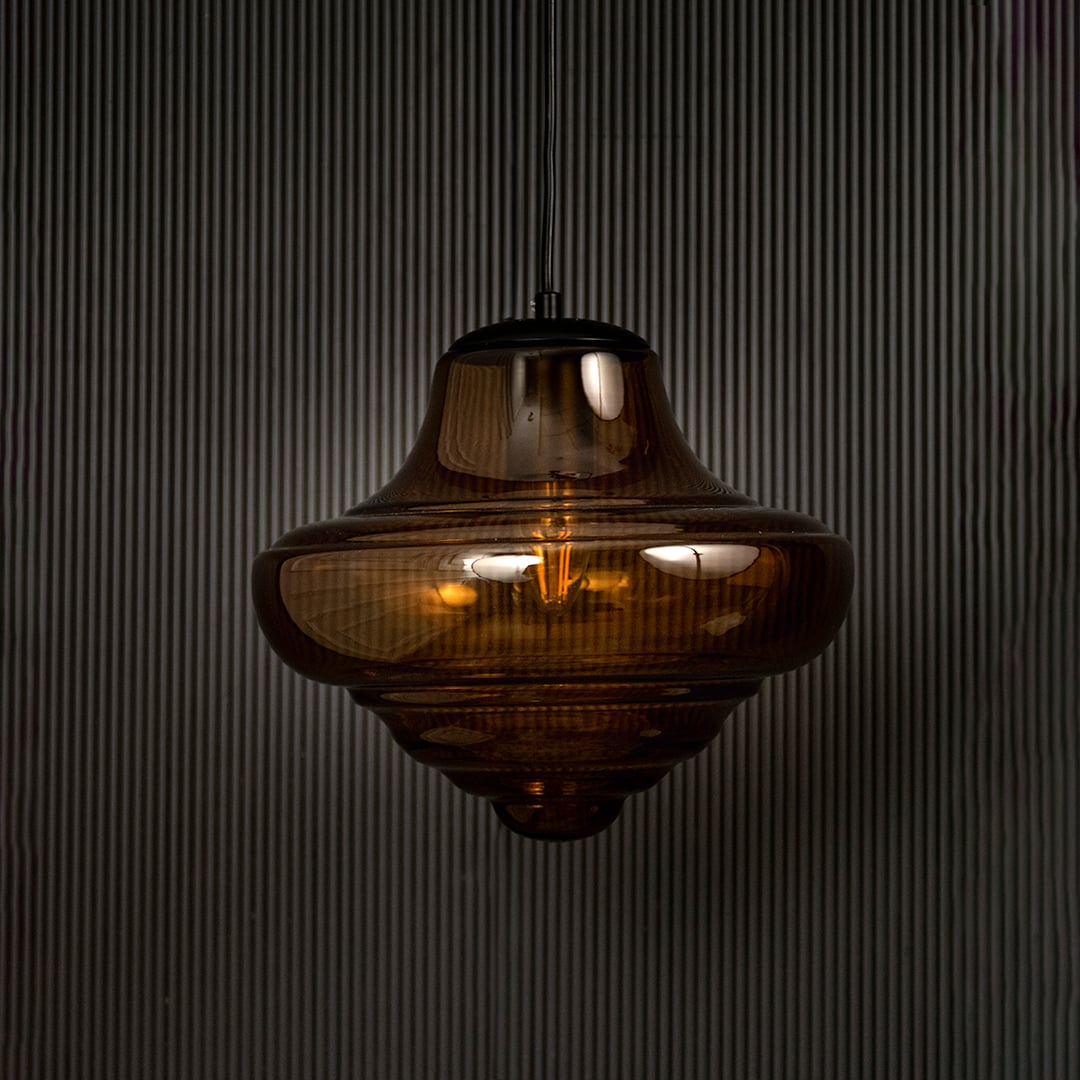 Amber glass pendant light displayed on dark background with light off emphasizing artistic design and premium glass finish.