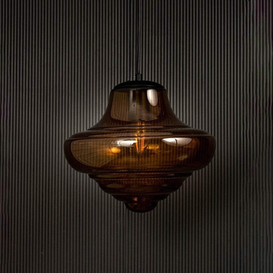 Amber glass pendant light displayed on dark background with light off emphasizing artistic design and premium glass finish.