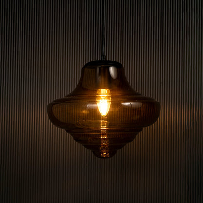 Elegant amber glass pendant hanging light illuminated on dark background highlighting glossy texture and warm ambient lighting style.