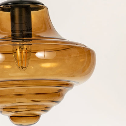 Close view of amber glass pendant light showing polished glass texture soft curved edges and detailed craftsmanship quality.