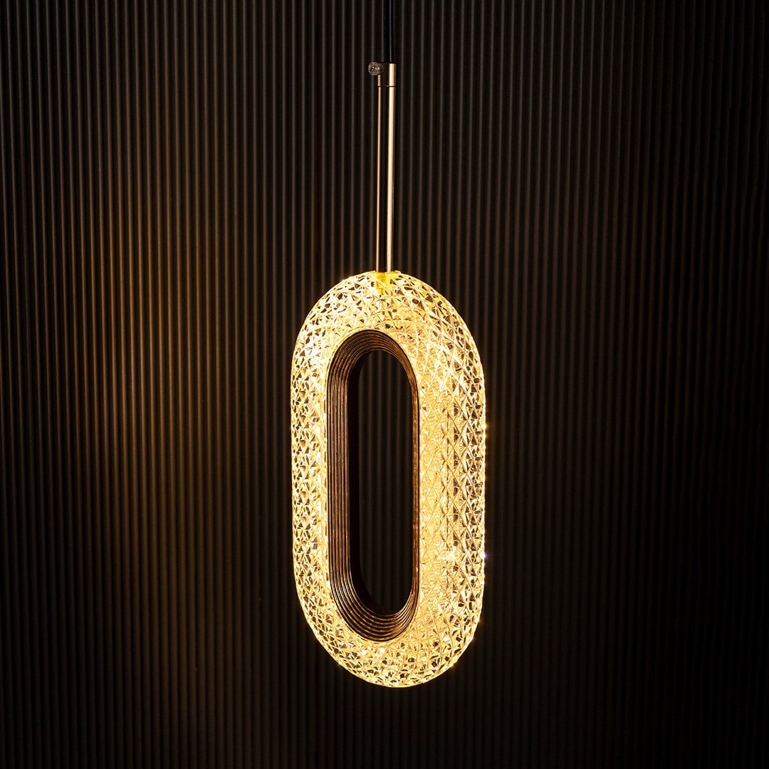 Crystal oval pendant lamp illuminated on black background highlighting golden detailing for a rich elegant look.