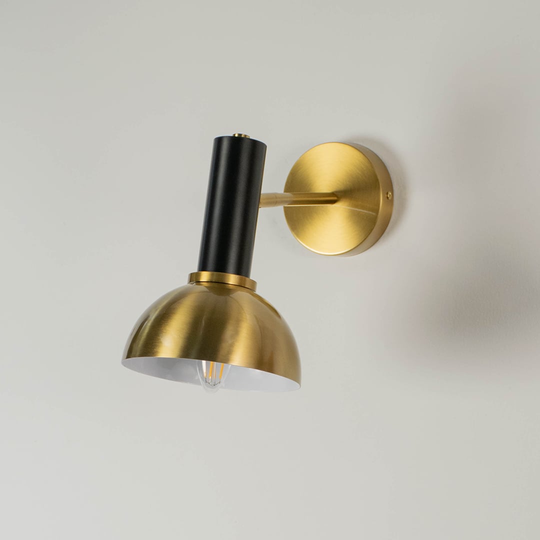 Gold and black wall light displayed without illumination against a white background showcasing its sleek dome design and elegant finish.