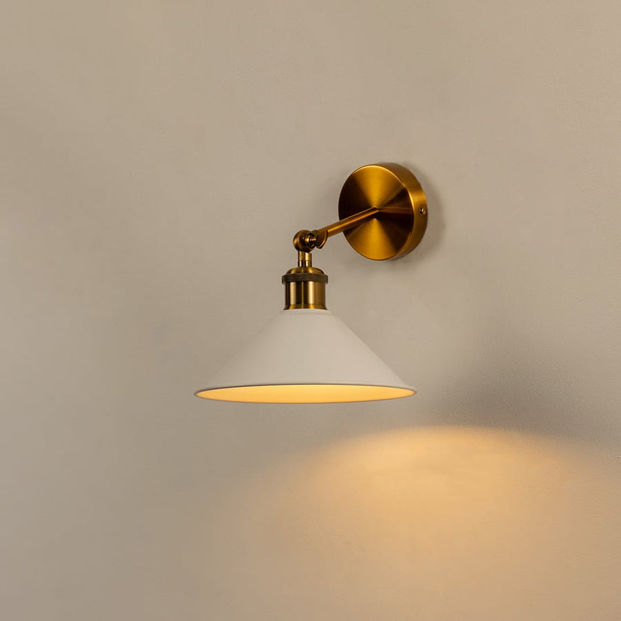White cone wall light with brass fixture glowing warmly on white wall bringing modern elegance to minimalist interiors.