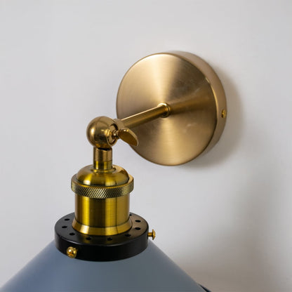 Closeup of matte grey wall light with brass mount showing smooth cone shade and fine detailing for luxury decor.