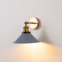 Grey cone wall light with brass base glowing on white wall adding elegant industrial style to modern living interiors.