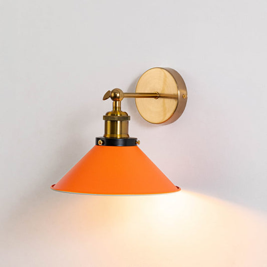 Orange cone wall light with brass fixture glowing on white wall adding warm color and elegance to modern interior decor.